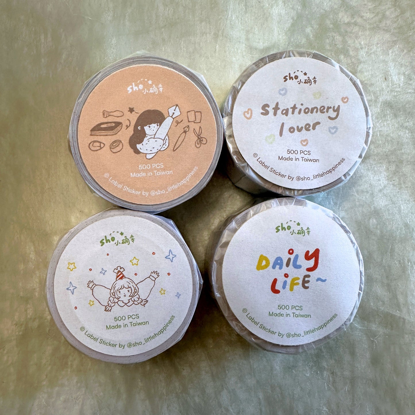 Four sticker tape rolls on a textured surface